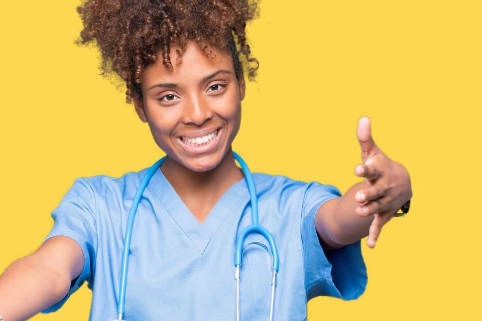 Young african american doctor woman over isolated background looking at the camera smiling with open arms for hug. Cheerful expression embracing happiness.
